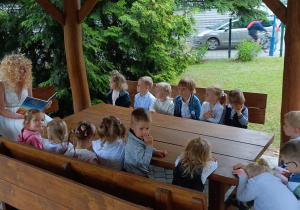 Przedszkolaki podczas czytania w altanie.
